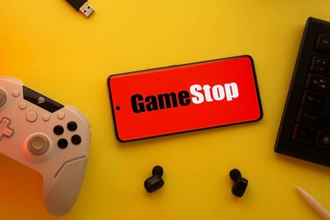 Dhaka, Bangladesh- 15 July 2025: Smartphone with GameStop logo, game controller, and earbuds on a