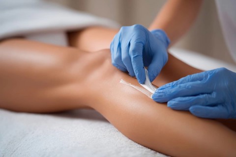 Bikini waxing of a beautiful young attractive woman in a spa. Luxury treatment for perfect skin and