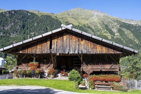 Colourful floral decorations and crucifix at a rustic alpine hut, Ridnauntal, South Tyrol, Italy