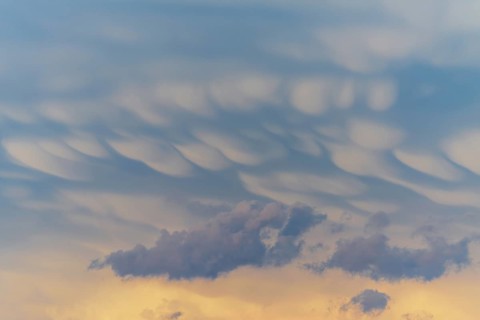 Unusual cloud structures create captivating shapes against a backdrop of warm colours as the sun