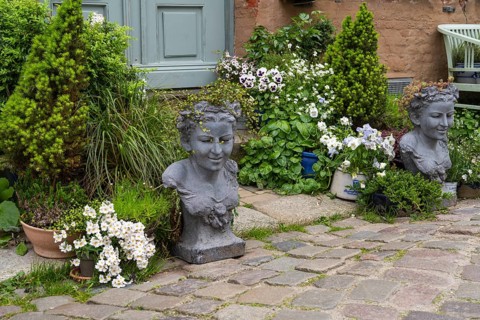House entrance with blooming flowers, conifers and stone busts, Old Town, Husum, North Frisia,