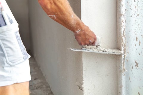 Plasterer smoothing and levelling interior walls