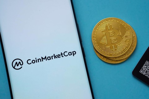 Dhaka, Bangladesh- 22 June 2025: Coinmarketcap logo on smartphone screen near Bitcoin coin and QR