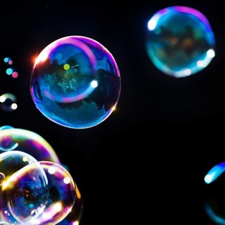 Iridescent soap bubbles in the colours of the rainbow against a black background, Recklinghausen,