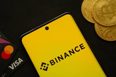 Dhaka, Bangladesh- 22 June 2025: Smartphone displaying Binance logo surrounded by Bitcoin coins and