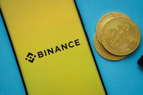 Dhaka, Bangladesh- 22 June 2025: Binance logo on smartphone screen near Bitcoin coin and QR code on