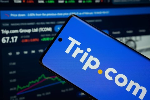 trello logo is displayed on a smartphone screen, with a stock graph webpage visible on a computer