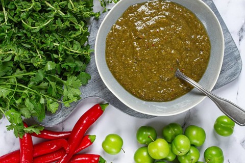 Tkemali sauce, made from green cherry plum, with ingredients on the table, top view, Georgian