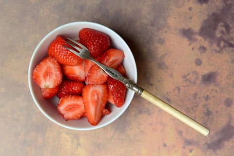 Sliced strawberries in hull with fork, Fragaria