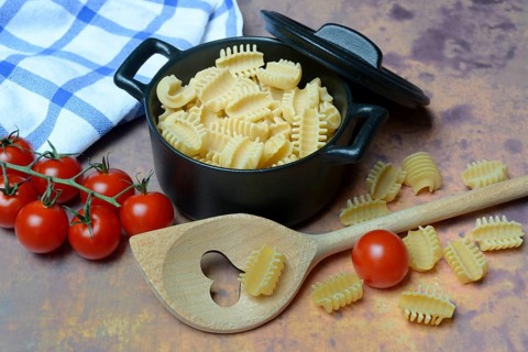 Italian pasta, Radiatori variety, in pots and heart-shaped cooking spoon