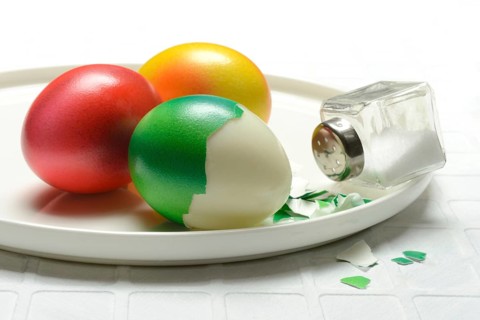 Easter eggs and salt shaker on plate, partially peeled