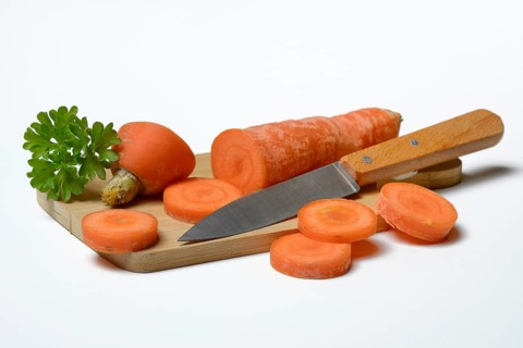 Carrot, carrot slices with kitchen knife on wooden board