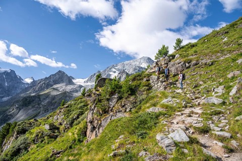 Three mountaineers on a hiking trail, mountain landscape near Arolla, behind mountain peak Mont
