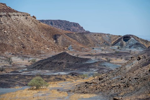 Dry landscape with yellow grass and black volcanic hills, Burnt Mountain, Damaraland, Kunene,