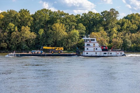 Tennessee Valley Authority tug boat Freedom pushing a barge with construction equipment upstream on