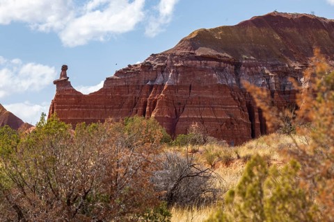 The Lighthouse rock hoodoo behind a field of grass and shrubs at Palo Duro Canyon State Park near