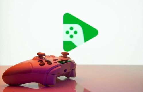 A close-up of a gamepad with the Google Play Games seen on screen in the background