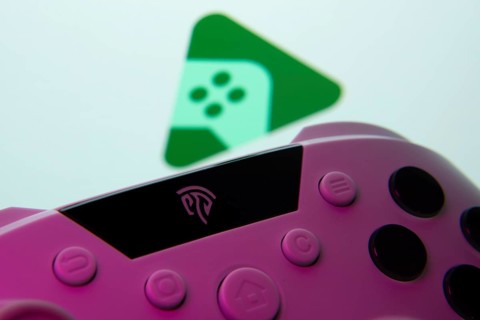 A close-up of a gamepad with the Google Play Games seen on screen in the background