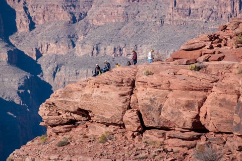 Visitors climb on rock formation rising above the canyon at Guano Point in Grand Canyon West near