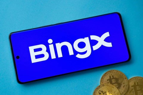 Smartphone displaying BingX logo with Bitcoin coins on a blue background