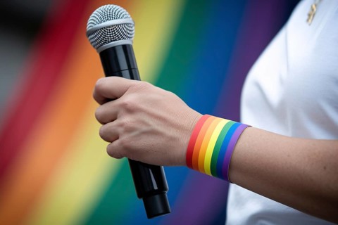 Rainbow wristband on a person holding a microphone during pride activism. Generative AI, AI