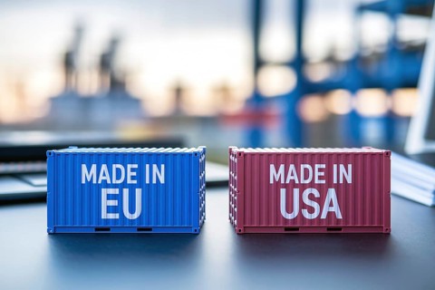 Trade war concept. Small cargo shipping containers with text Made in EU and Made in USA with blurry