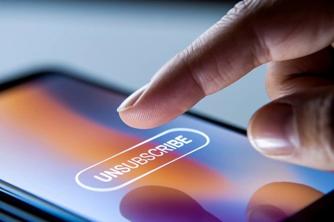 Close up of person's finger hovering over unsubscribe button on mobile phone screen. Generative Ai,