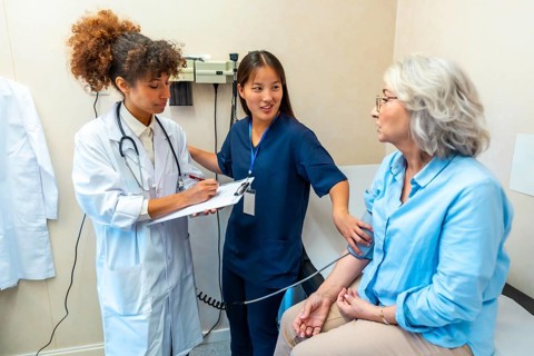 Medical professionals taking care of elderly woman's health, performing blood pressure check during