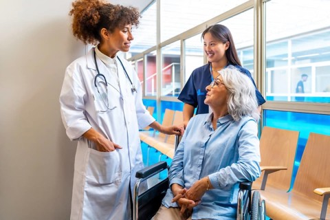 Medical professionals providing care and support to an elderly patient in a wheelchair,
