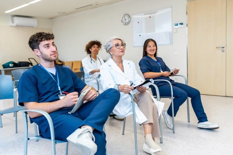 Healthcare professionals listening attentively during a medical conference, taking notes and