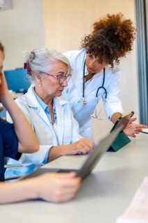 Medical professionals collaborating on a tablet, discussing patient cases and sharing expertise