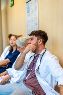 Group of medical professionals sitting in a hospital hallway, feeling exhausted after a long shift