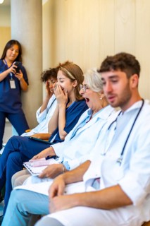 Exhausted doctors and nurses yawning while sitting in a hospital hallway, waiting for their next
