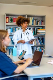 Doctors and nurses using laptops and tablets during a medical briefing, discussing patient charts