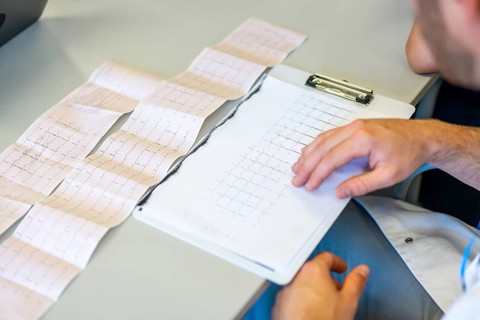 Doctor examining electrocardiogram printout, focusing on heart health and medical diagnosis in