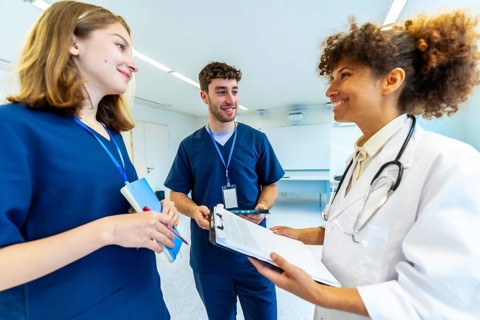Doctor and nurses reviewing medical records, collaborating on patient care in a bright hospital