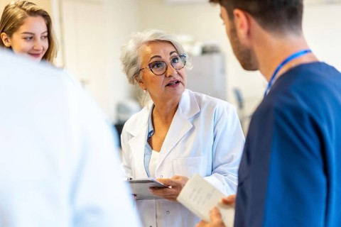 Senior female doctor briefing medical staff during a hospital meeting, discussing patient care