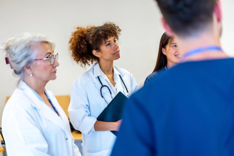 Doctors and nurses engaging in a medical staff meeting, attentively listening to a speaker while