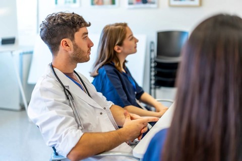 Medical professionals attending a conference in a hospital meeting room, listening to a