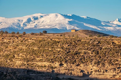 View over the slopes of the Gorafe desert, snow-covered Siera Nevada, Gorafe Desert, UNESCO Granada