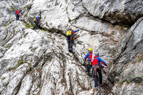 Mountain rescuers from Bergwacht Bayern climbing a steep rock face on Hoher Göll, Berchtesgaden,