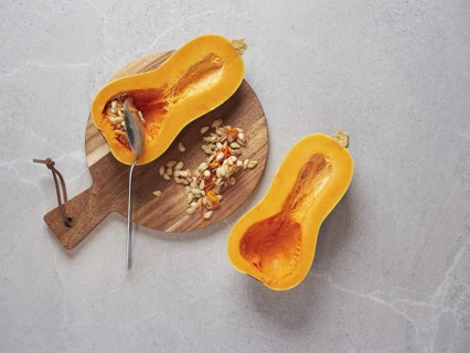 Remove the seeds from a raw butternut squash cut in half using a metal spoon. Cooking techniques