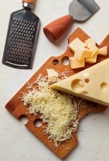 Grated cheese, Maasdam, on a cutting board, grater and cheese knife, close-up, no people