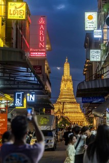 Wat Arun, Temple of Dawn at sunset with dark clouds. Boats on the Chao Phraya river. Tourist