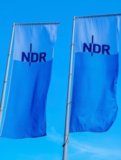 Two flags with lettering NDR, Norddeutscher Rundfunk, flagpoles, colours blue white, light wind,