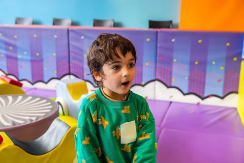 Young boy expressing amazement while playing in a colorful and stimulating indoor playground,