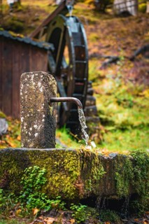 Historic Streinbrunnen fountain with mill wheel in autumn, Bad Wildbad, Kurpark, Black Forest,