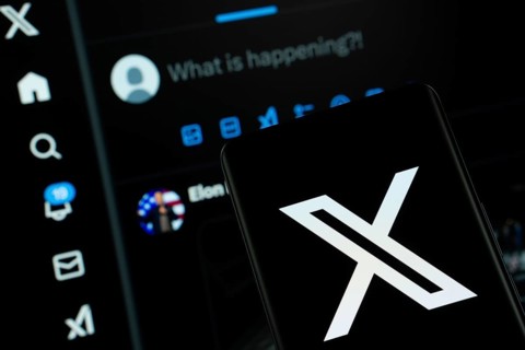 X (twitter) logo is seen on a smartphone, with the bluesky website visible on a computer screen in