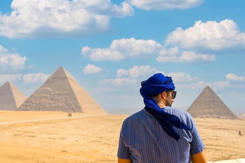 A young tourist wearing blue turban and sunglasses enjoying the Pyramids of Giza, the oldest