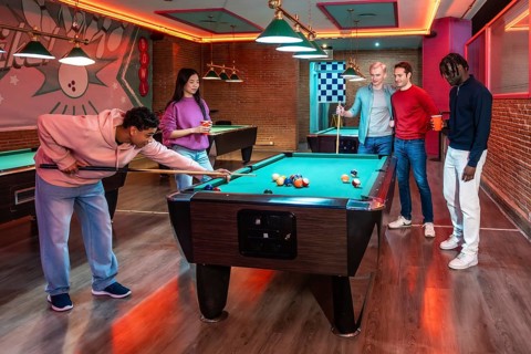 Group of multi ethnic friends enjoying a game of billiards in a vibrant entertainment venue,